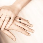 The hands of newlyweds with wedding rings as they hold hands.